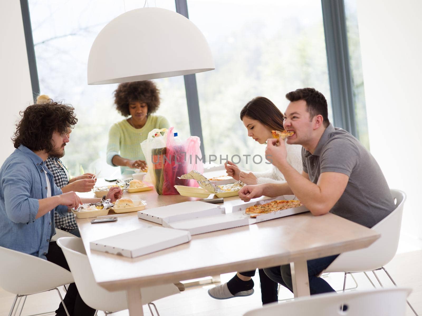 multiethnic group of happy friends spending time together with food and soda drinks, eating at home concept