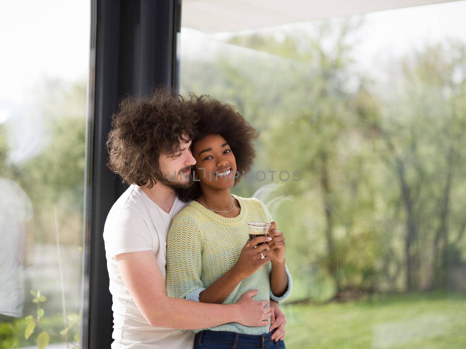 romantic happy young multiethnic couple enjoying morning coffee by the window in their luxury home