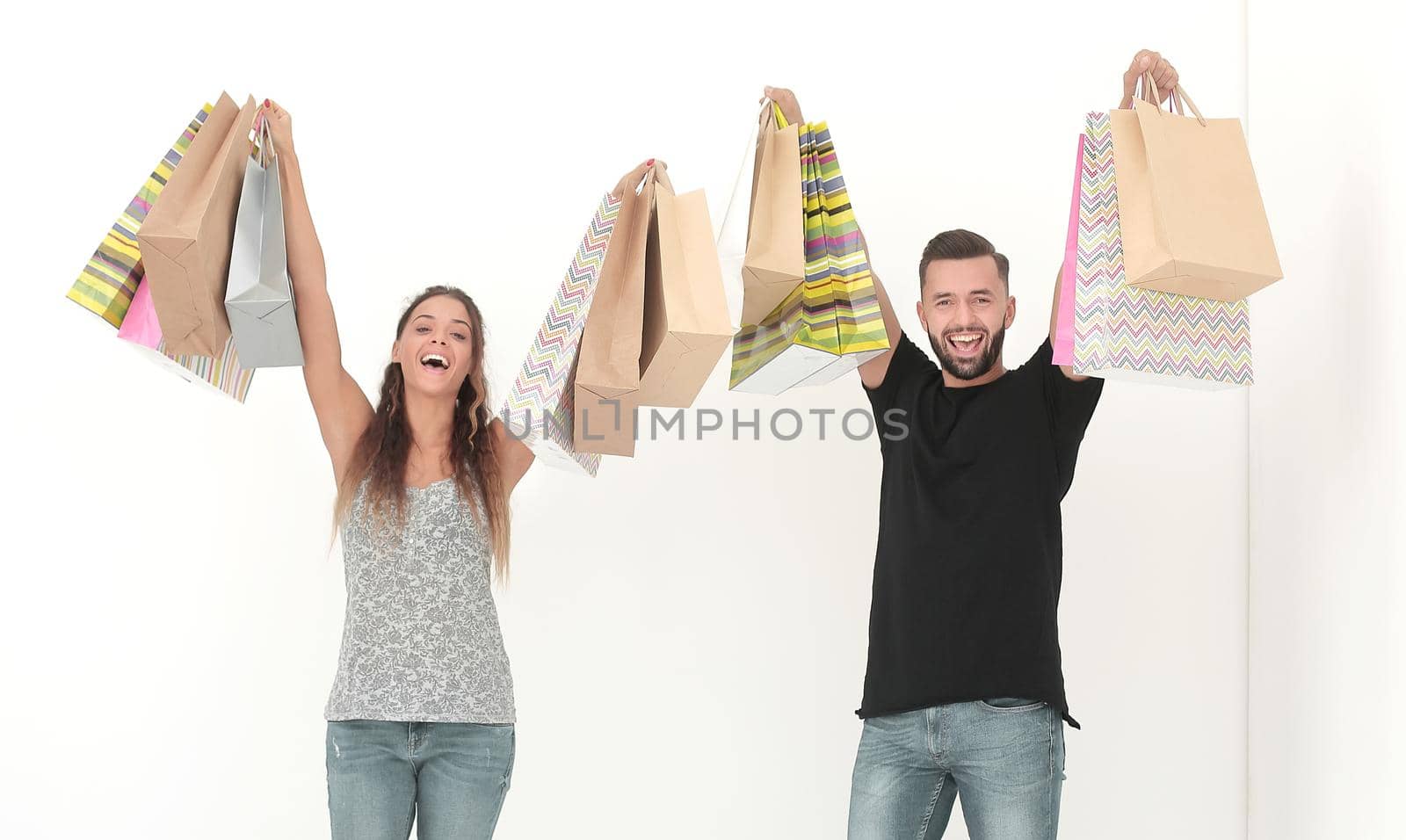 young couple holding shopping bags and looking at the camera isolated on white background