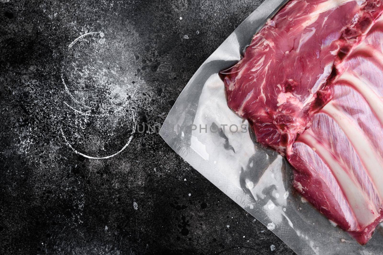 Lamb rib fresh meat Vacuum sealed set, on black dark stone table background, top view flat lay, with copy space for text