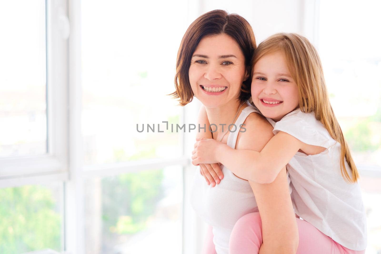Smiling Mother with her little daughter girl playing in light room