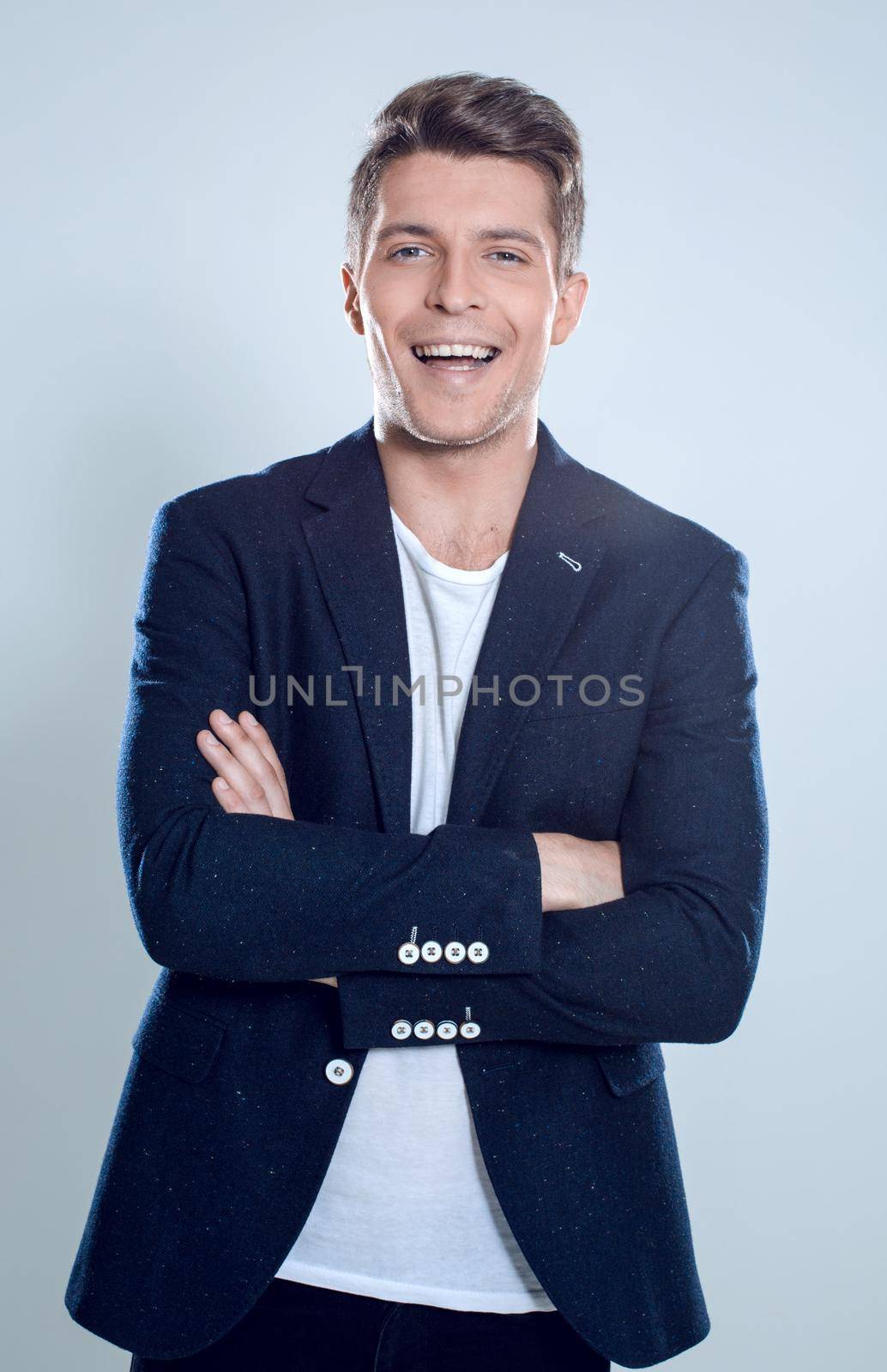 Happy smiling man with crossed arms pose, with blank copyspace area for text or slogan, against grey background