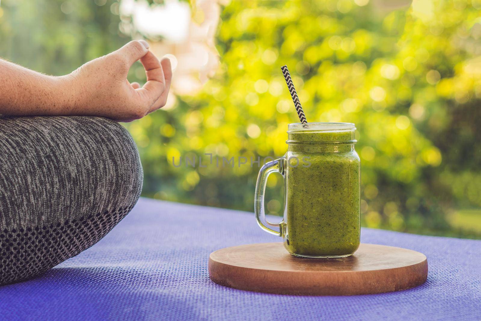 Closeup of a woman's hands during meditation with a green smoothies of spinach, orange and banana by galitskaya