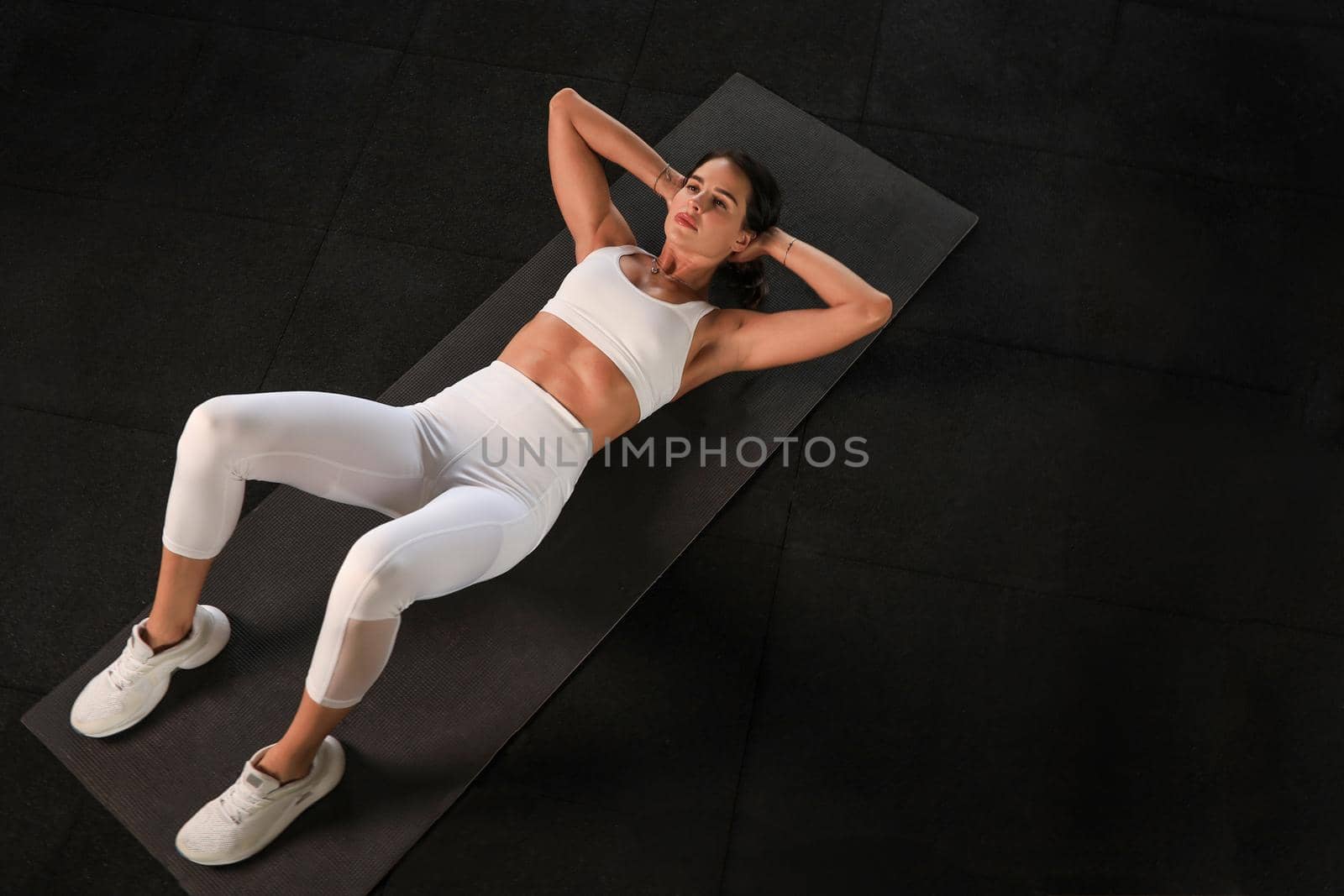 Young woman in sportswear doing crunches at the gym, top view. by tsyhun