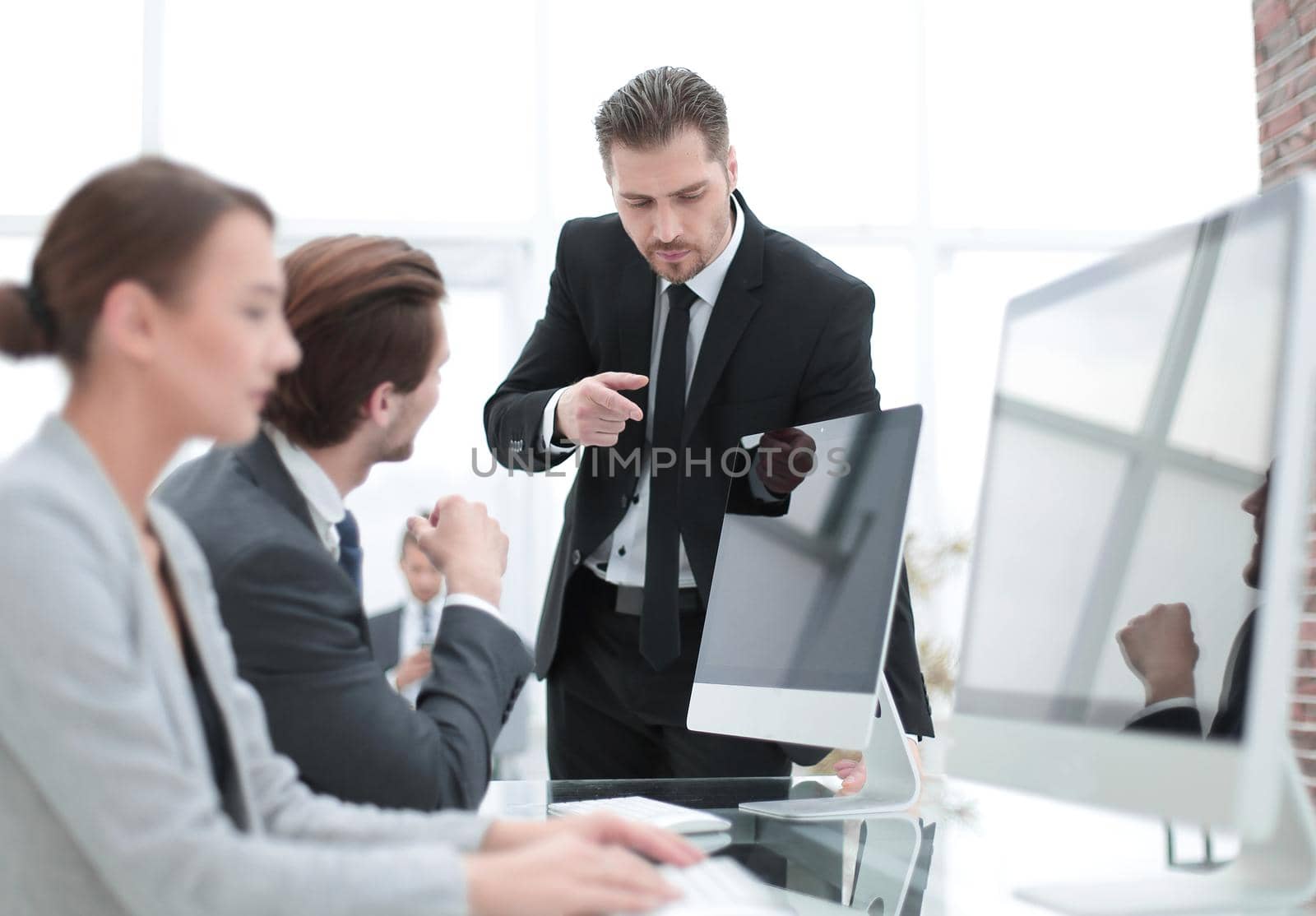 businessman talking with employees standing near the desktop.office weekdays