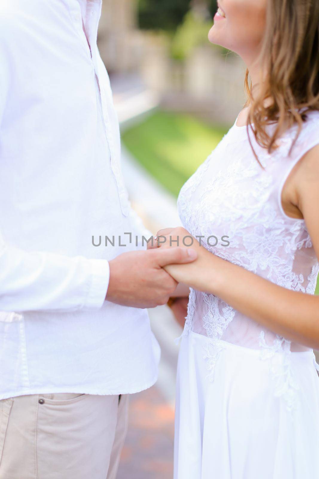 Happy american bride and groom holding hands and standing outside. by sisterspro