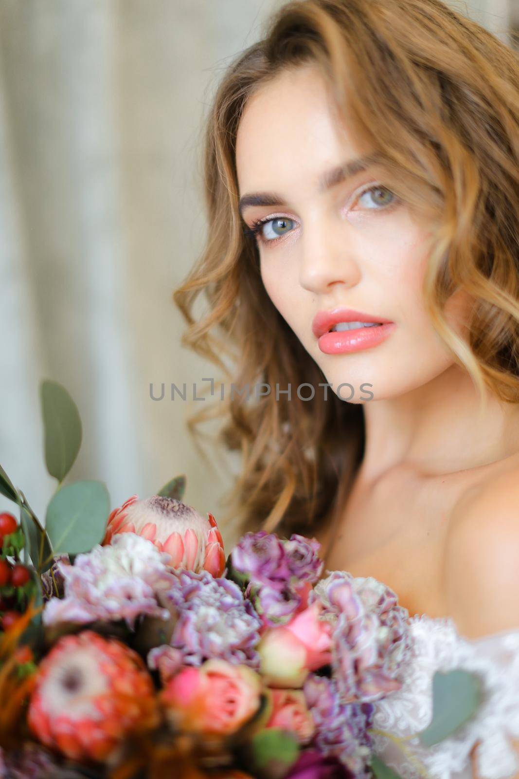 Close up portrait of charming bride with bouquet of flowers at studio. Concept of floristic art, beauty and beautiful wedding photo session.