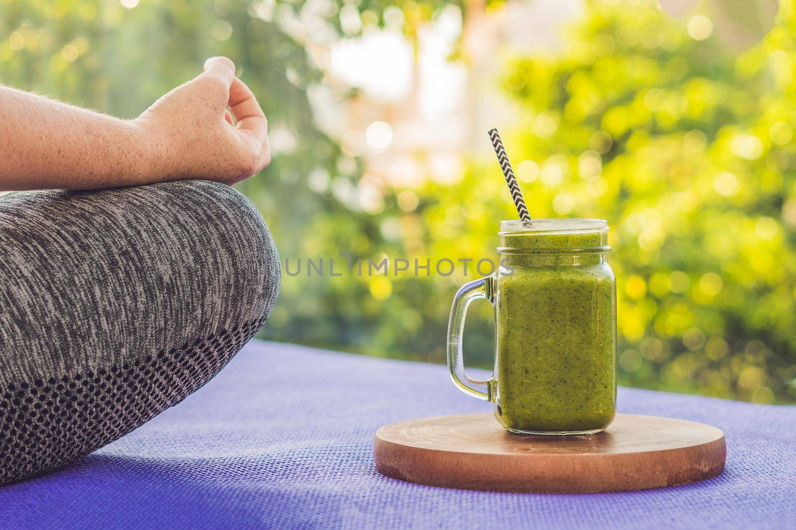 Closeup of a woman's hands during meditation with a green smoothies of spinach, orange and banana by galitskaya