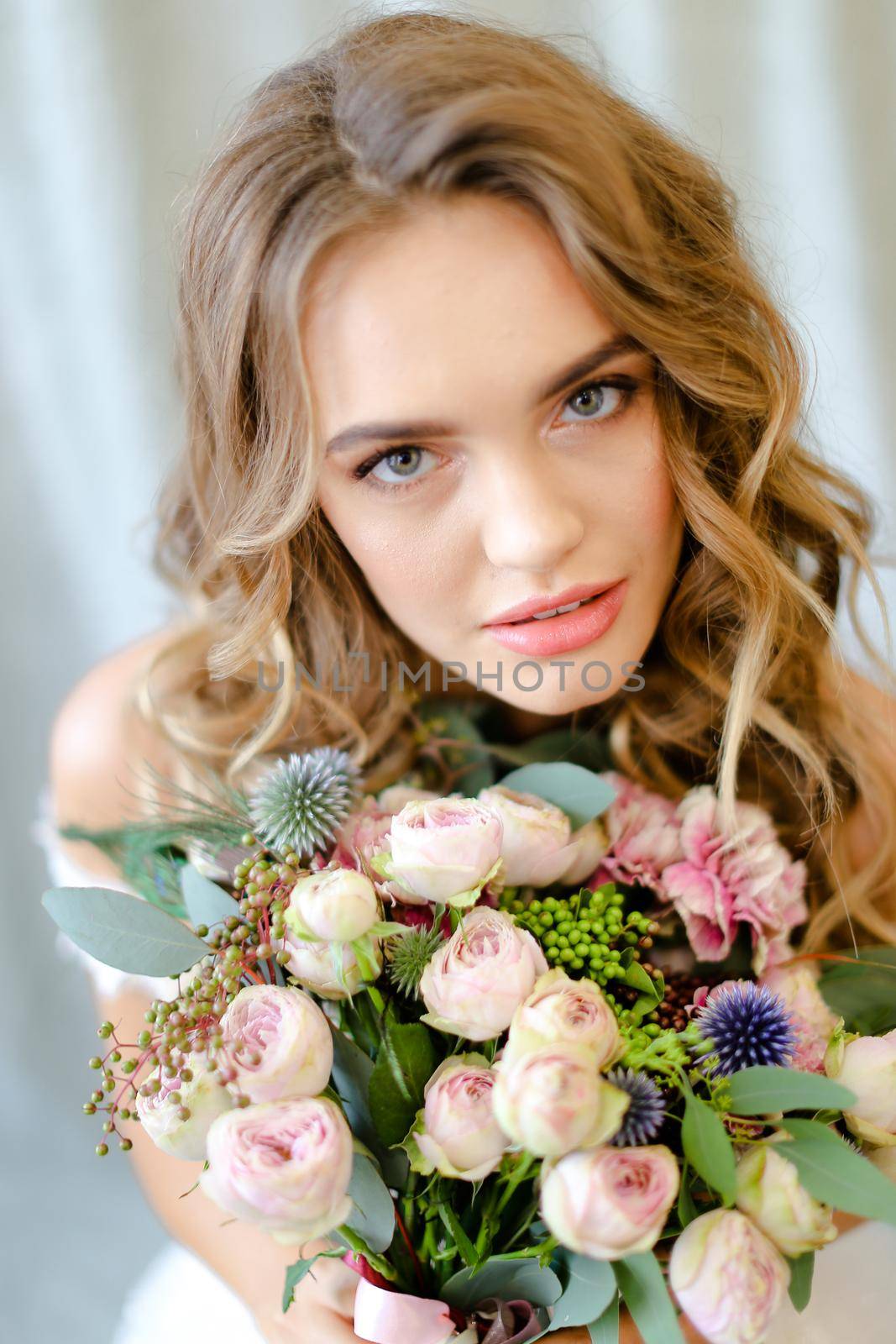 Close up portrait of young pretty bride with bouquet at studio. Concept of bridal photo session and floristic art.