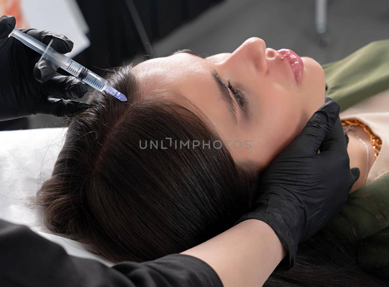 Young woman with hair problem receiving injection in head skin in a clinic. Mesotherapy treatment of hair loss, injection for hair growth by Mariakray