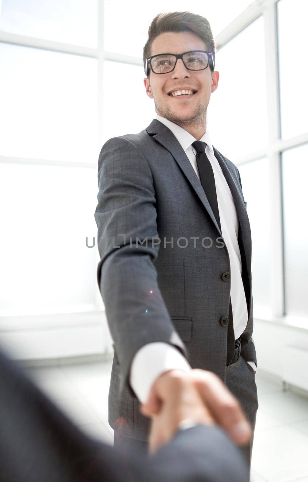 young businessman smiling and standing in office. concept of handshakes