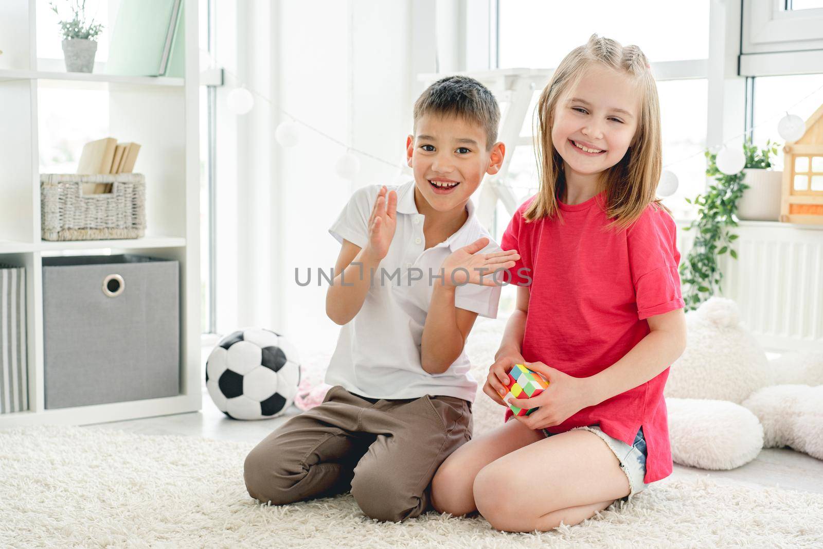 Happy children playing at home sitting on floor in light room