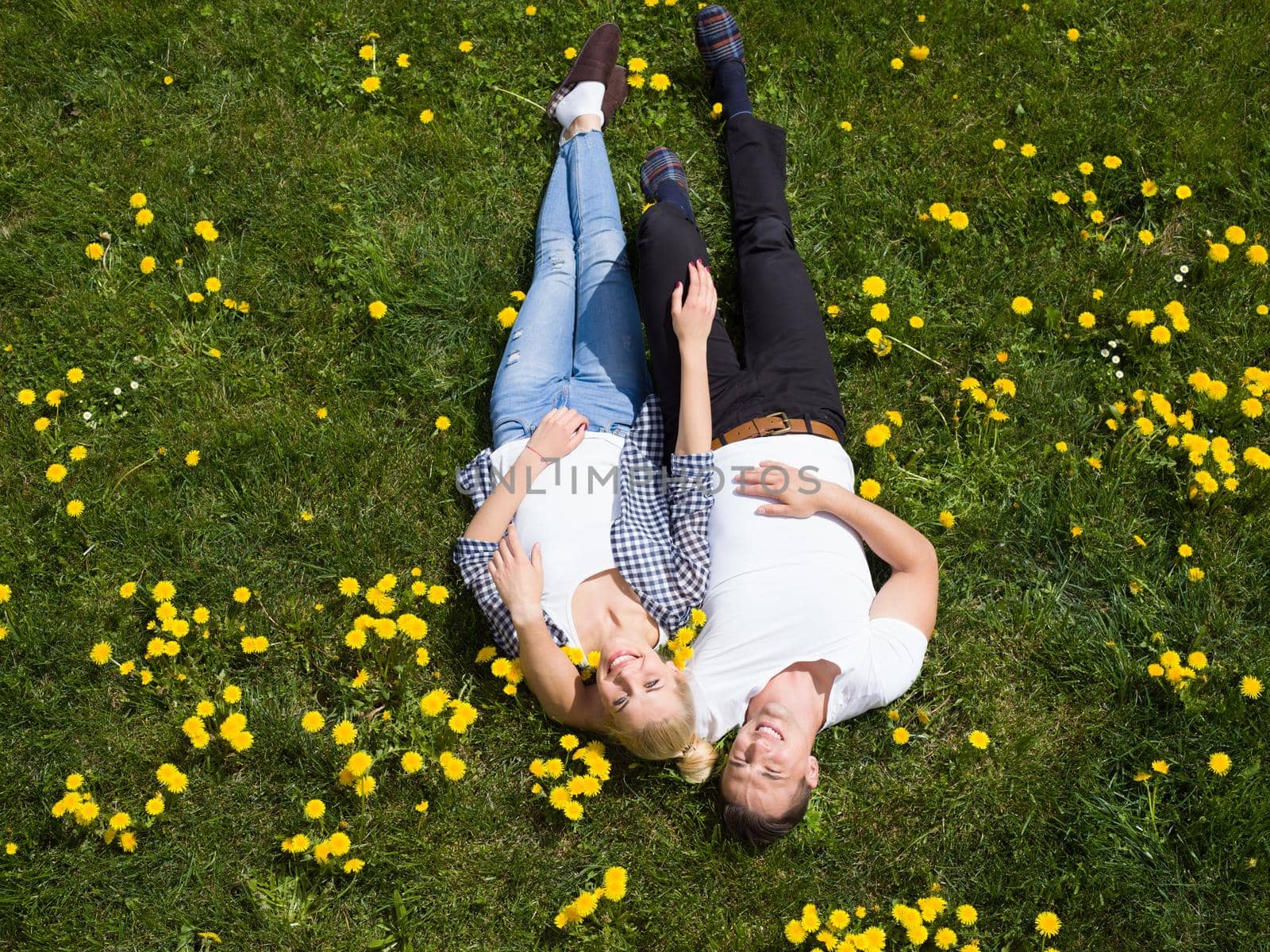 Overhead view of young man and woman lying on the grass, Top view of relaxed young couple lying down on meadow.