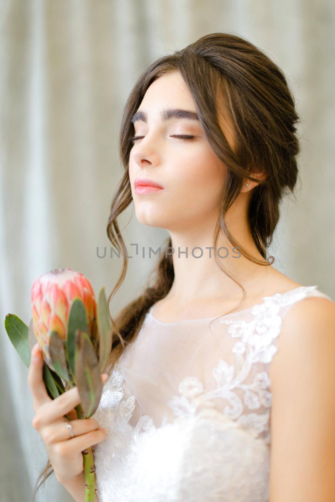 Portrait of nice beautiful brunette caucasian bride with flowers at studio. Concept of bridal photo session and bridal makeup.