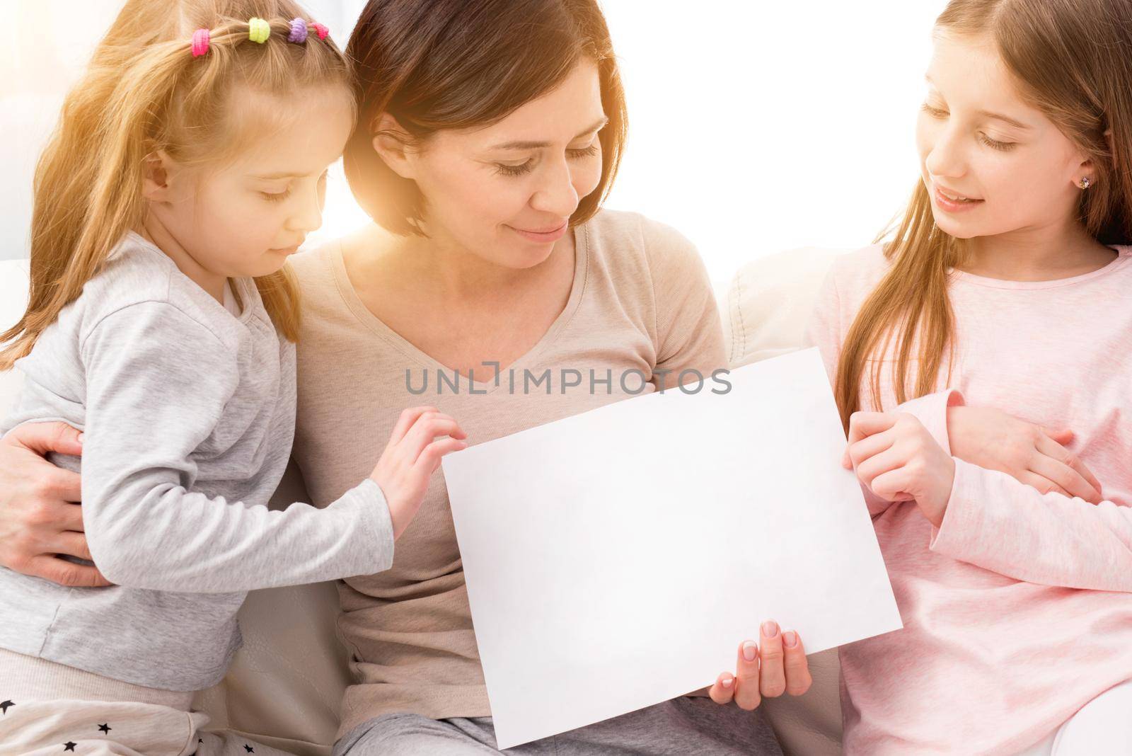 Family holding blank sheet of paper A4 for design at home