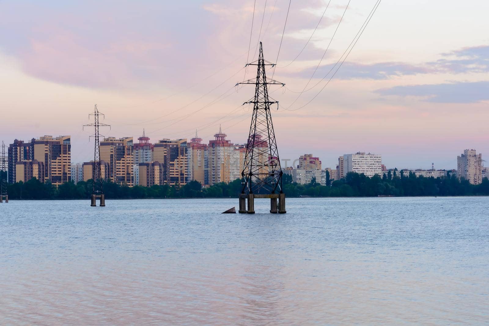 High-voltage power lines in water reservoir,high voltage electric transmission towers. Electrical power lines through a river at sunset. Voronezh Russia