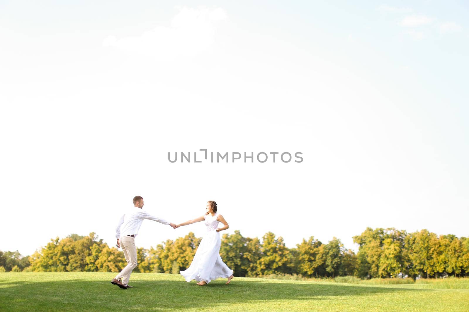 Groom and bride dancing and playing on grass. Concept of wedding photo session on open air and nature.