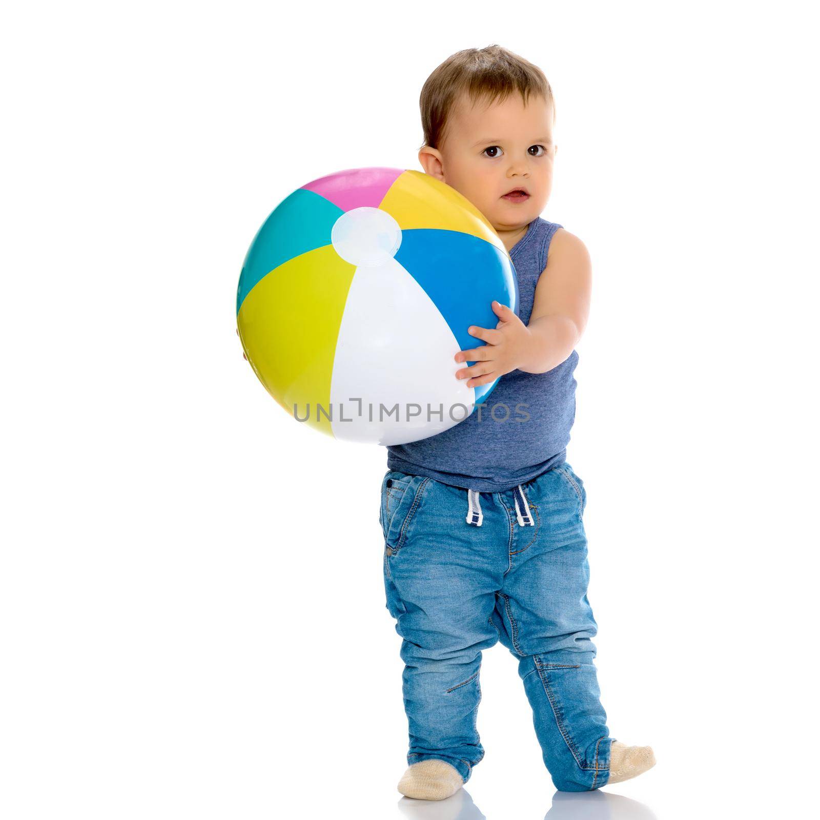 A cheerful little boy is playing with a ball in the studio on a white background. The concept of a happy childhood, game and sport. Isolated.
