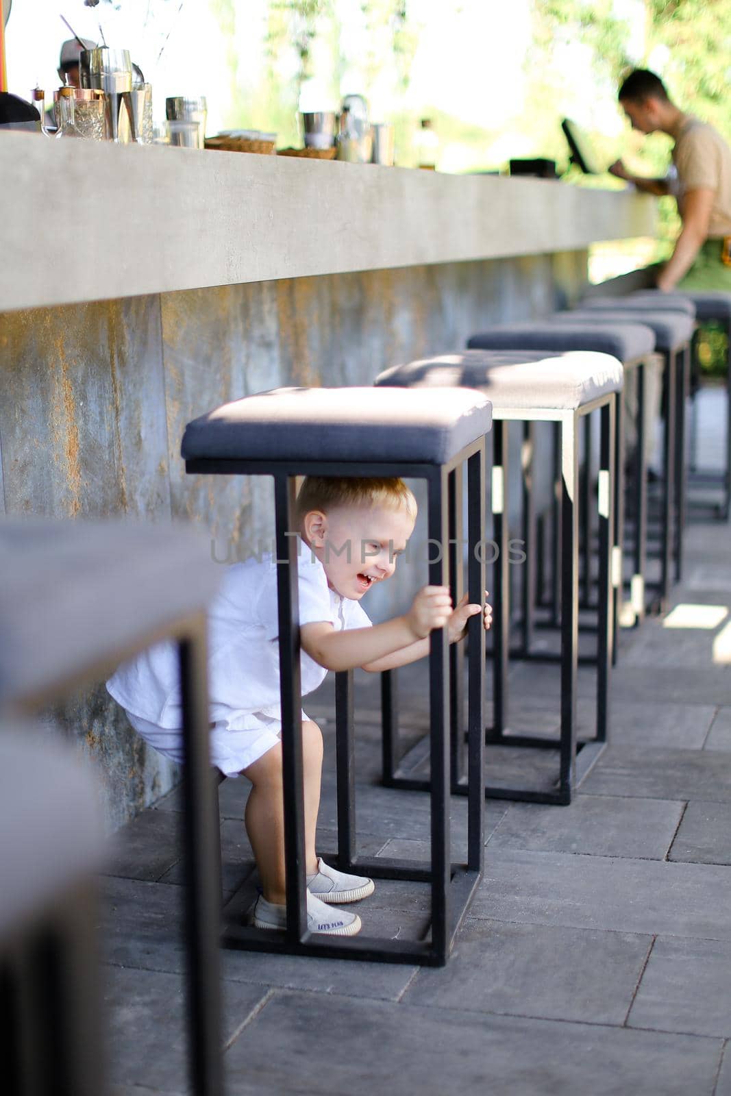 Little american male baby playing outside at street cafe. by sisterspro