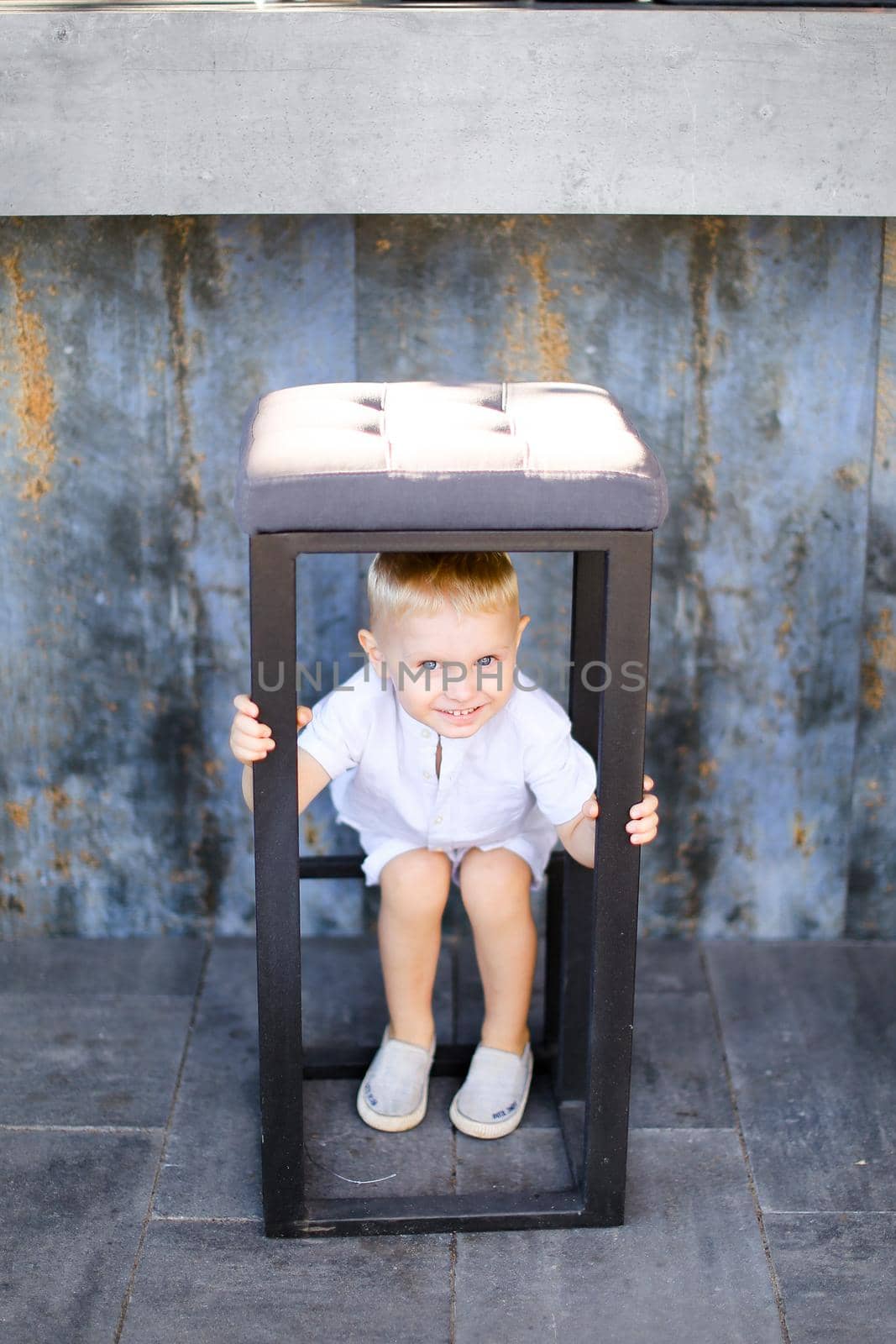 Little cute male baby wearing white clothes and playing outside. Concept of childhood.