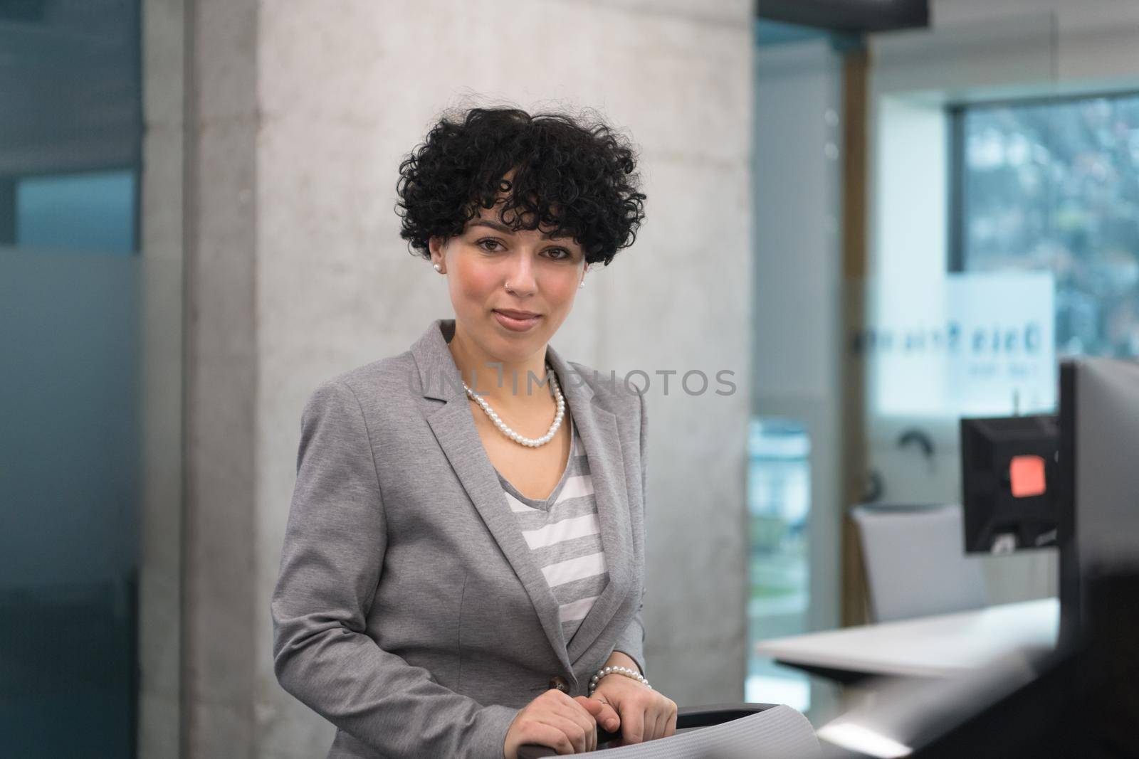 Portrait of successful female software developer with a curly hairstyle at modern startup office