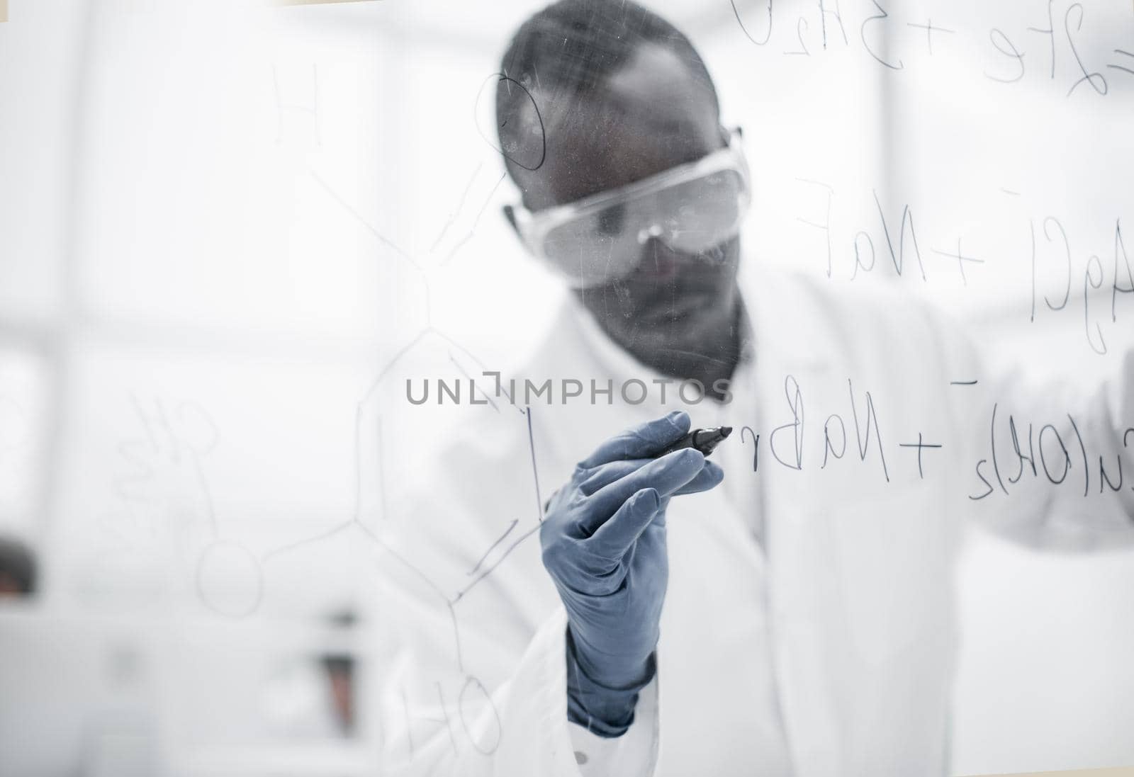 confident scientist writing a structural formula on a glass Board.photo with copy space