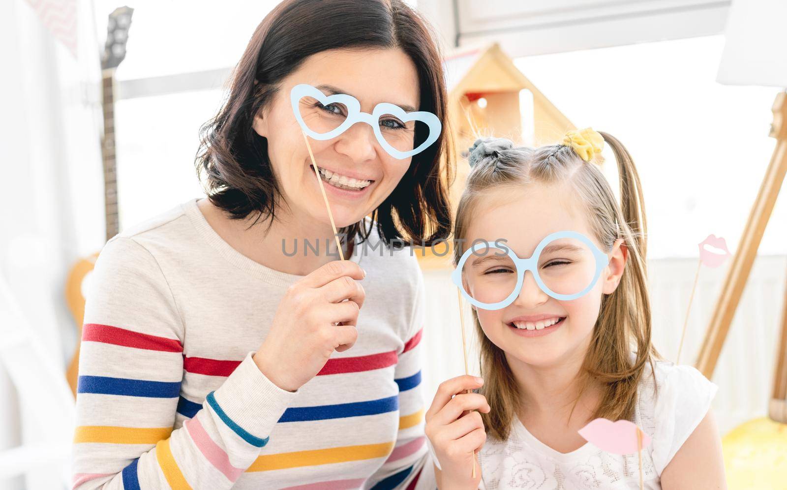 Portrait of smiling mother and daughter with stick glasses