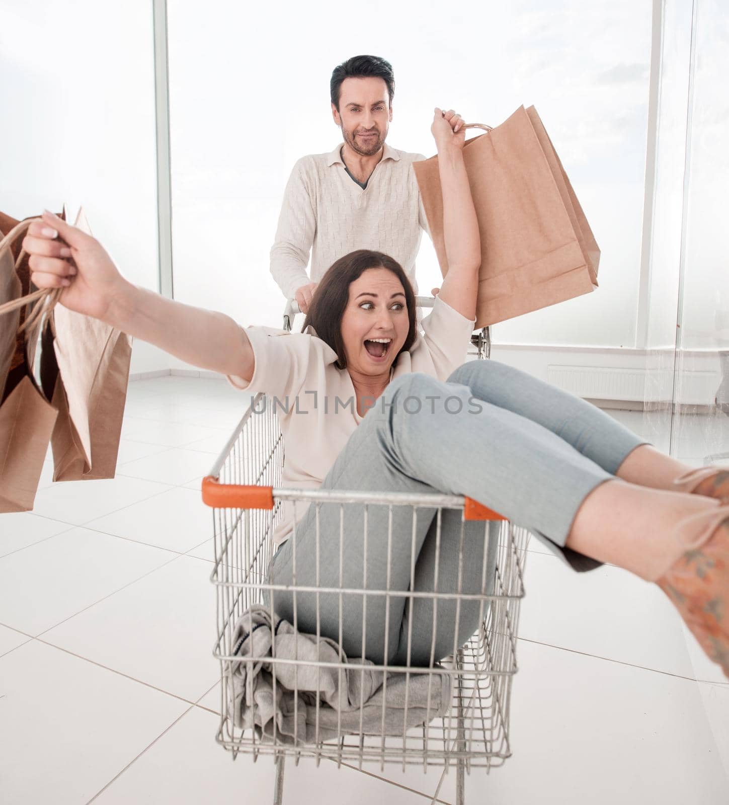 man carries his girlfriend in a shopping cart. photo with copy space