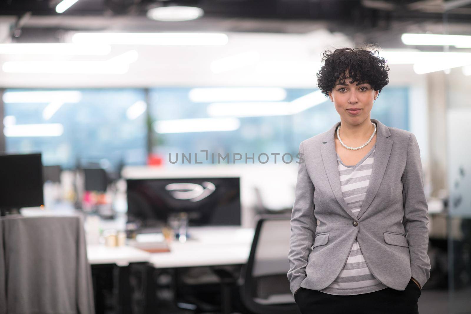 Portrait of successful female software developer with a curly hairstyle at modern startup office