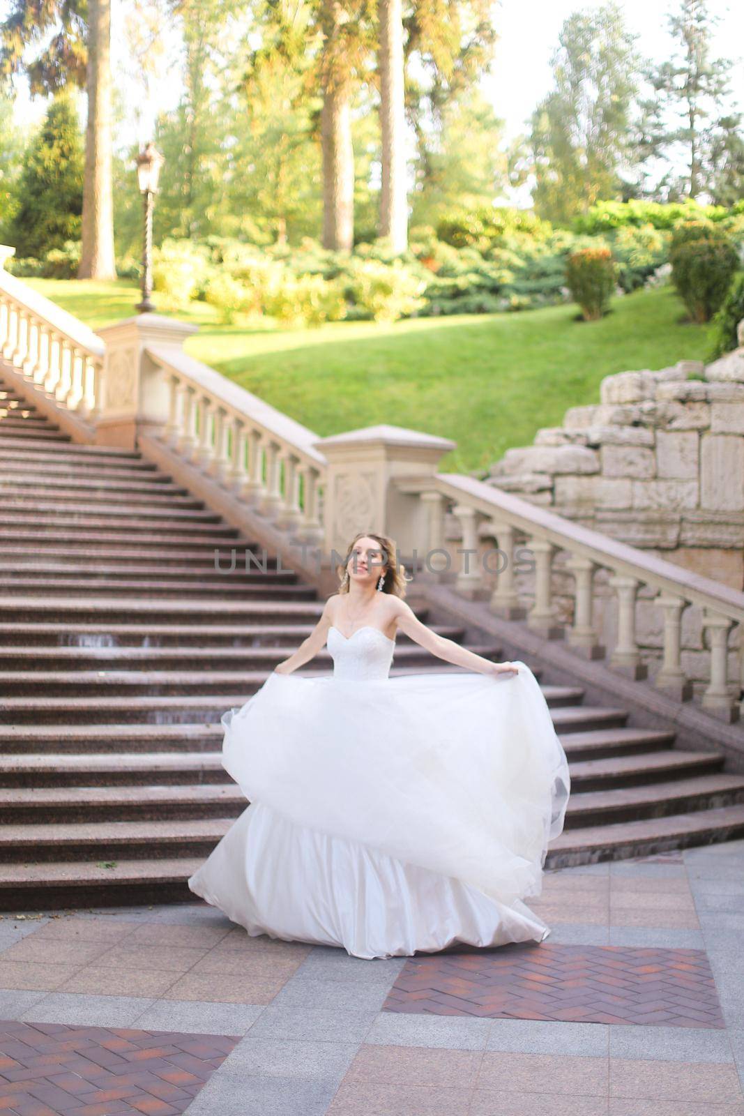 Beautiful bride in wite dress in concrete stairs background. Concept of wedding and bridal photo session.