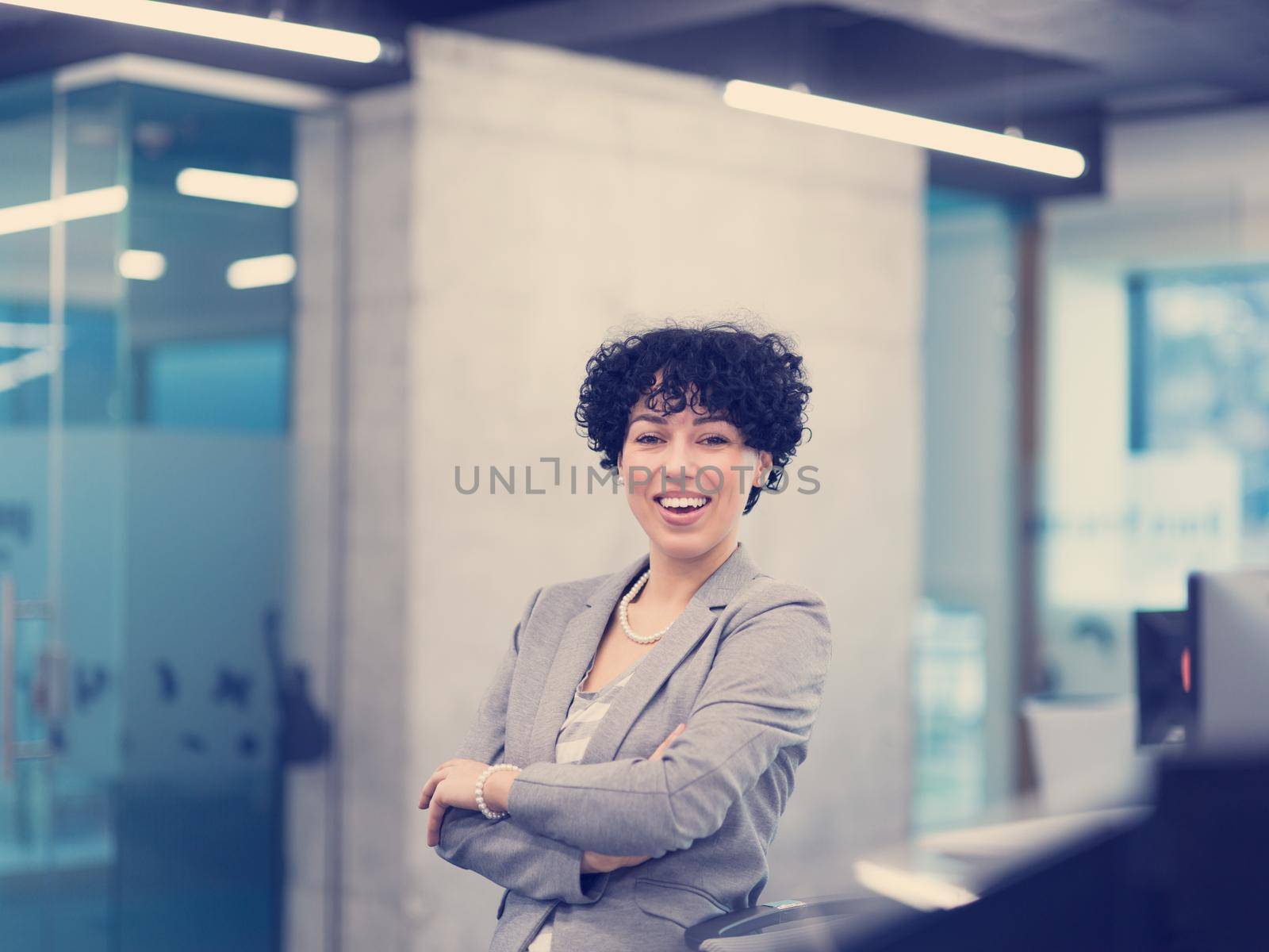 Portrait of successful female software developer with a curly hairstyle at modern startup office