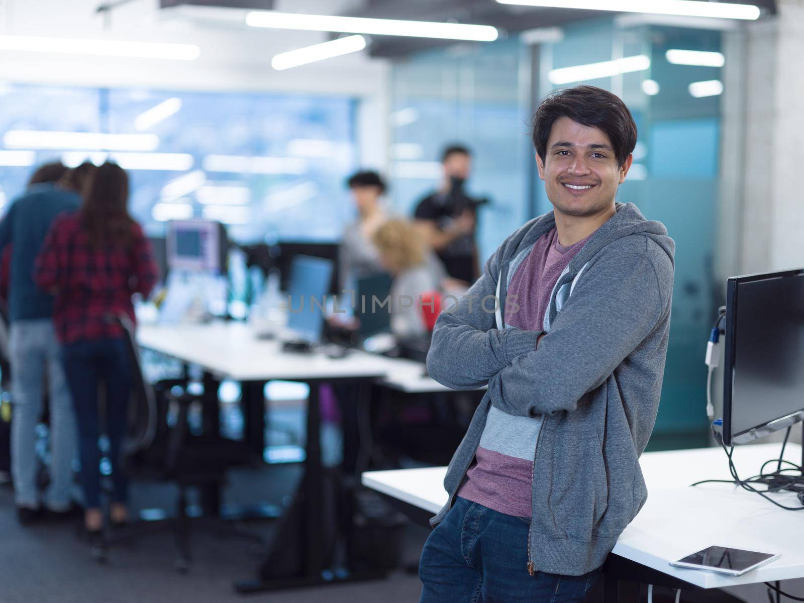 Portrait of young smiling successful male software developer standing at modern startup office