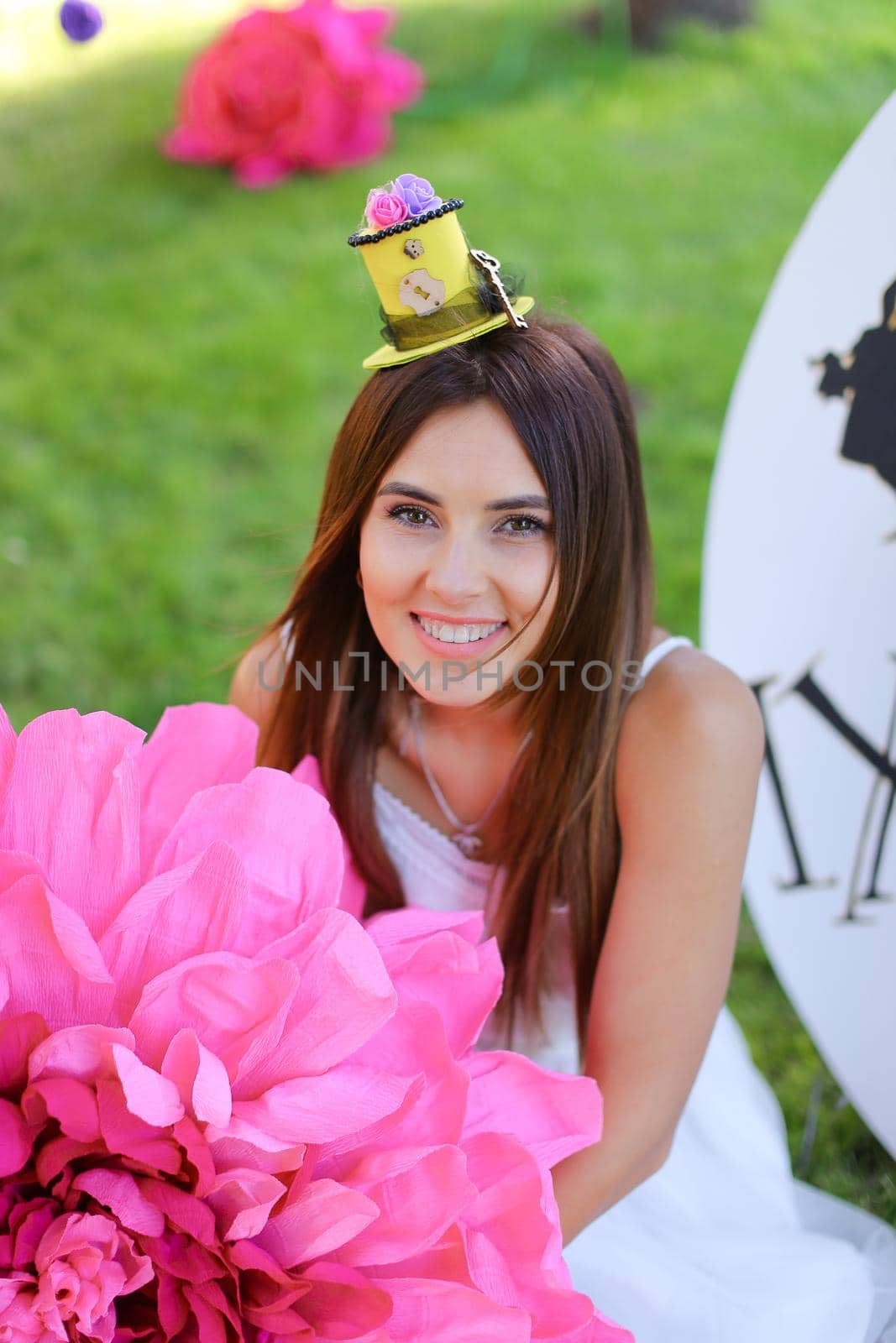 Young american girl sitting at decorated place for children near big pink flower. Concept of beauty and festive decorations.