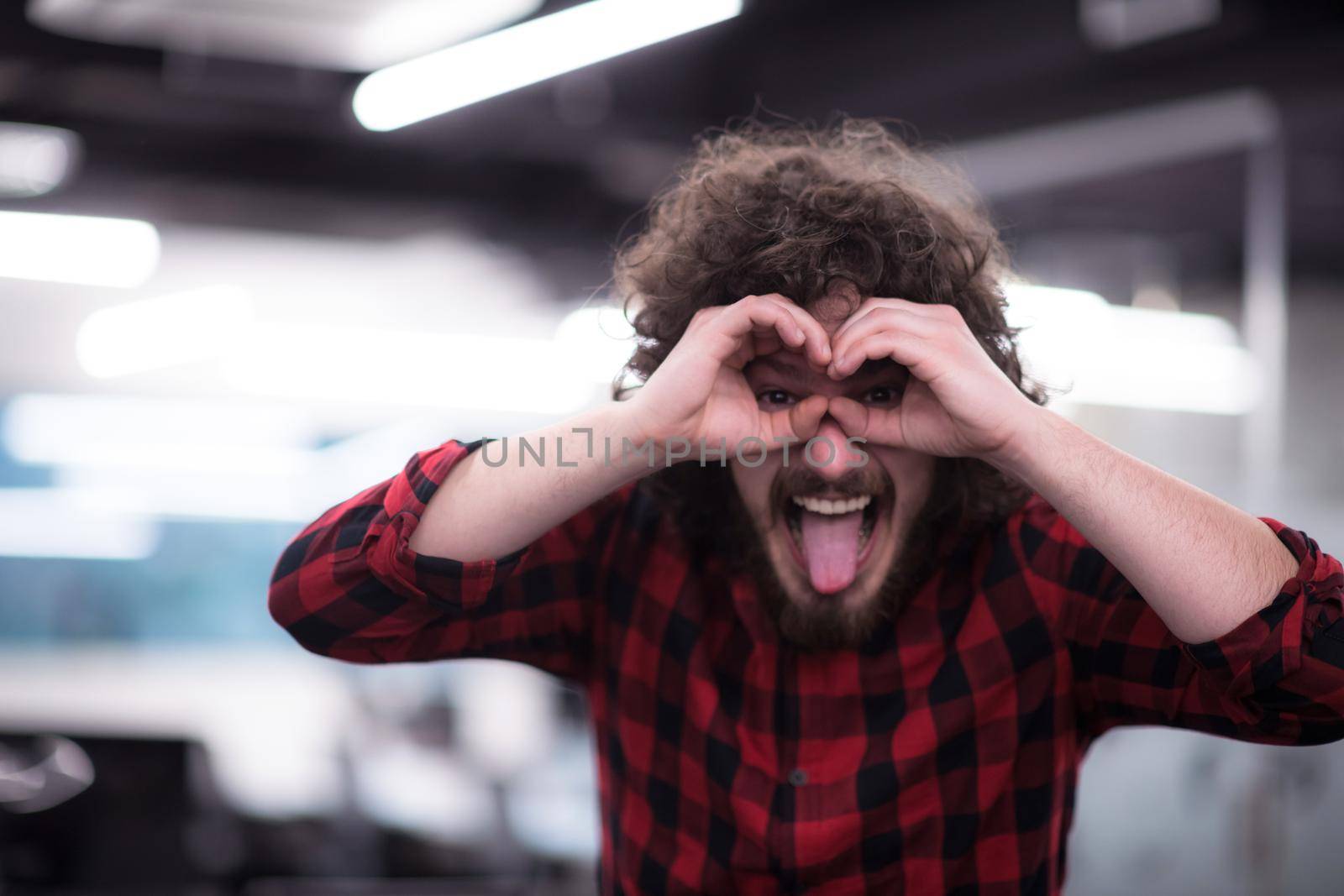 Portrait of young smiling successful male software developer standing at modern startup office