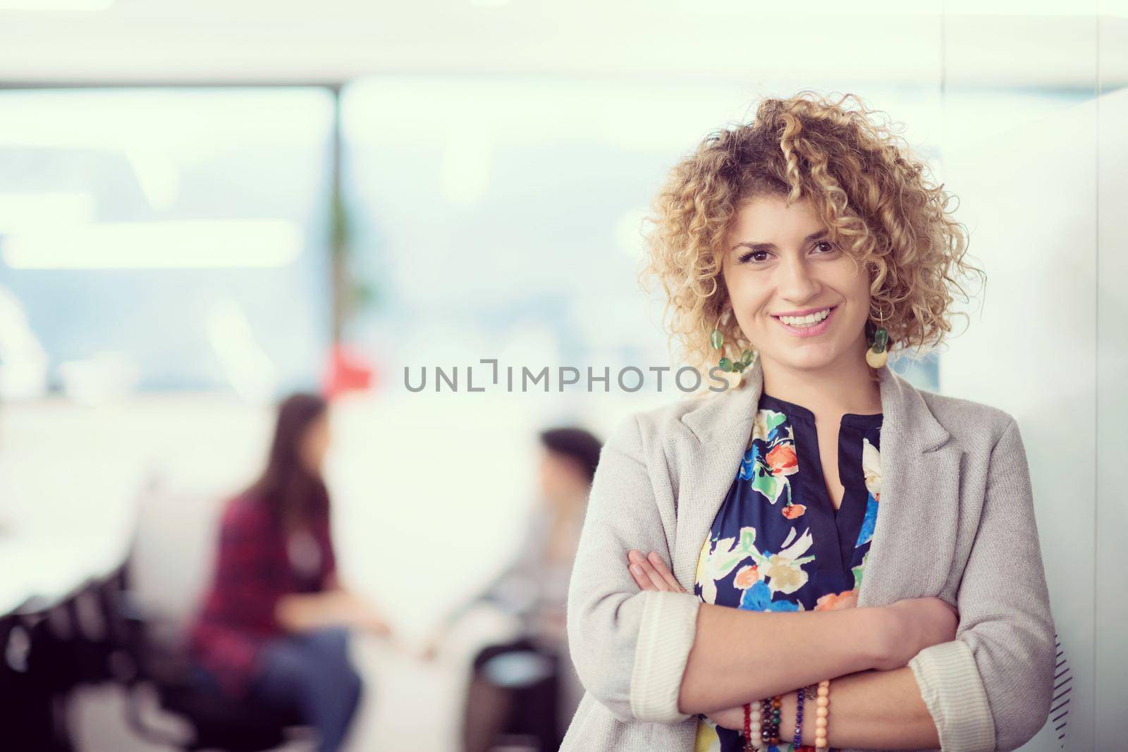 Portrait of successful female software developer with a curly hairstyle at modern startup office