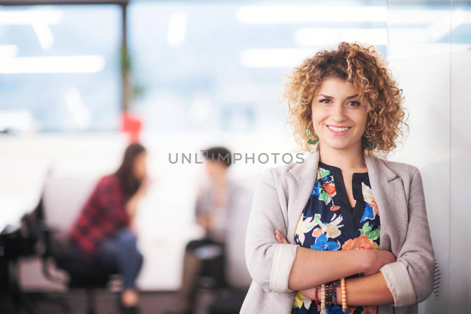 Portrait of successful female software developer with a curly hairstyle at modern startup office