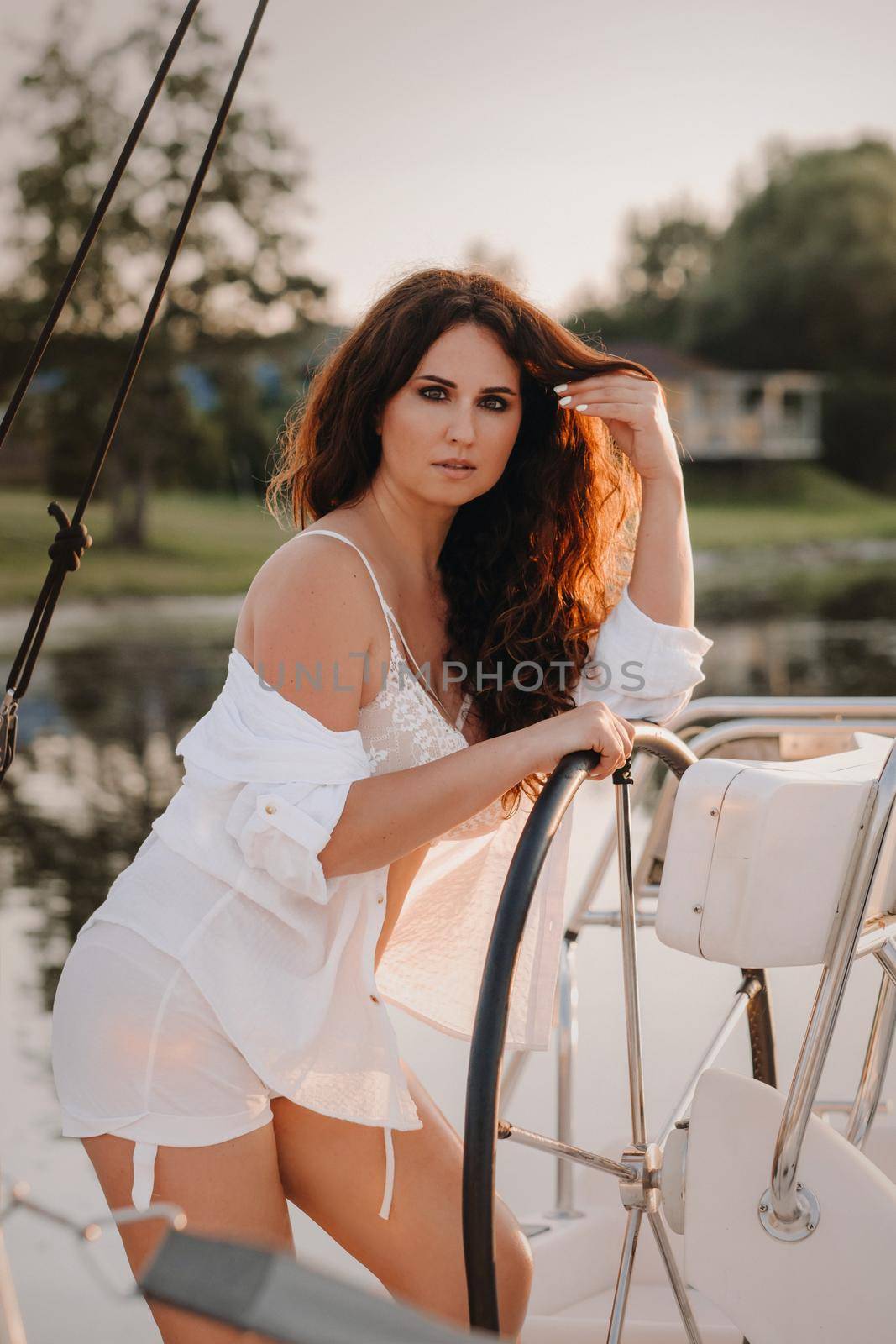 sexy woman in a white shirt enjoys the sunset on her private white yacht by Lobachad