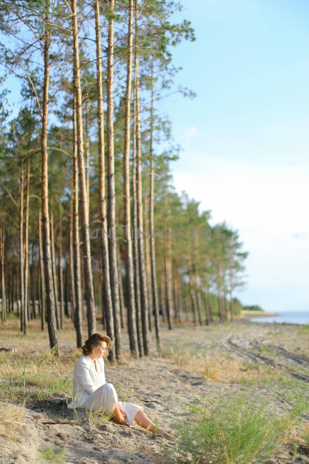 Young lady sitting on sand beach with trees in background. by sisterspro