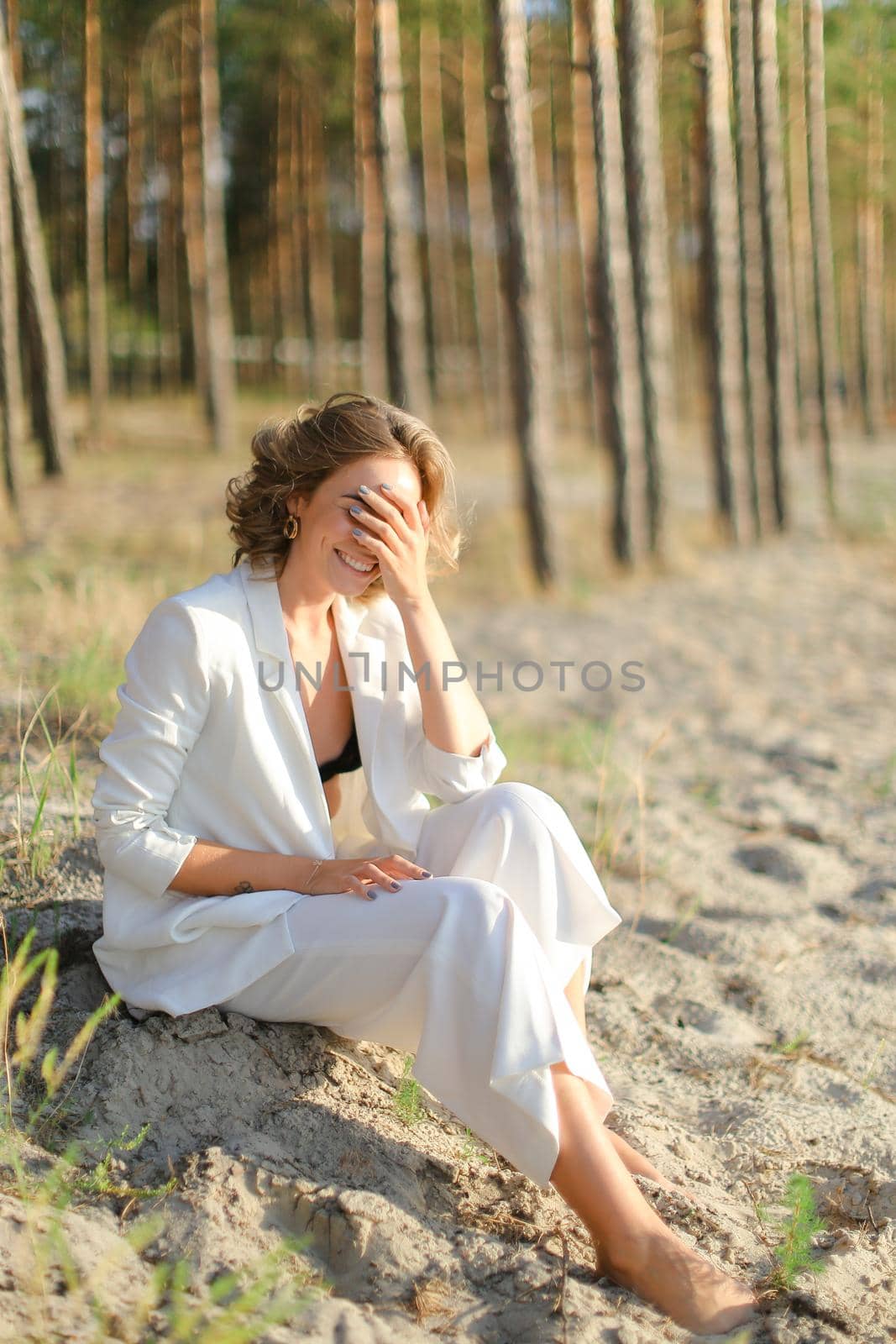 Young pretty woman sitting on sand beach with trees in background. by sisterspro