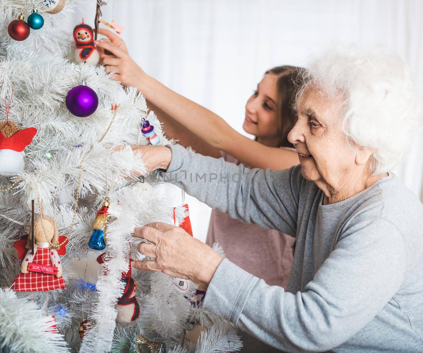 Granddaughter with grandma decorating christmas tree by GekaSkr