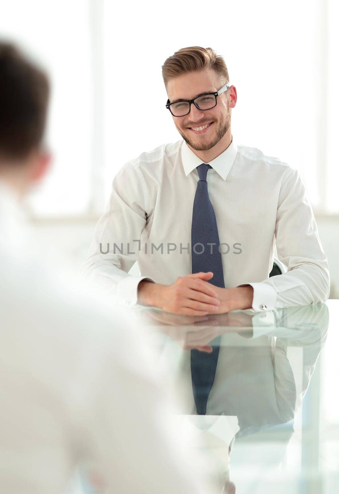 Manager talks to the employee sitting at his Desk.business concept