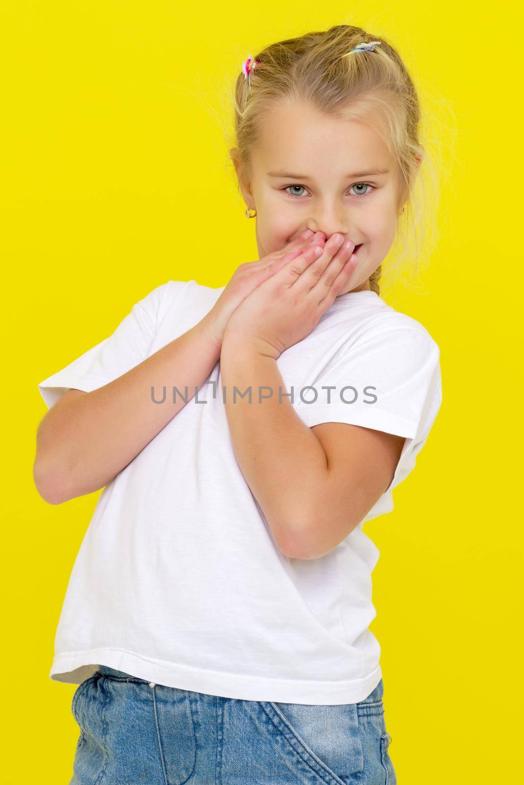 Emotional little girl in a clean white T-shirt. The concept can be used to advertise goods and services, whose logo can be printed on the surface of the shirt.On a yellow background.