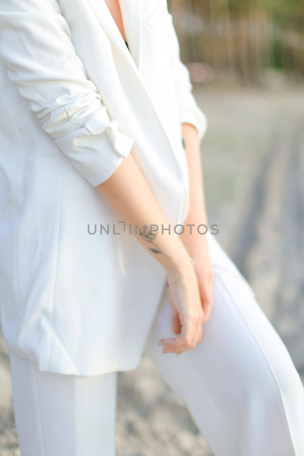 Close up female hands with little black tattoo in white clothes background.