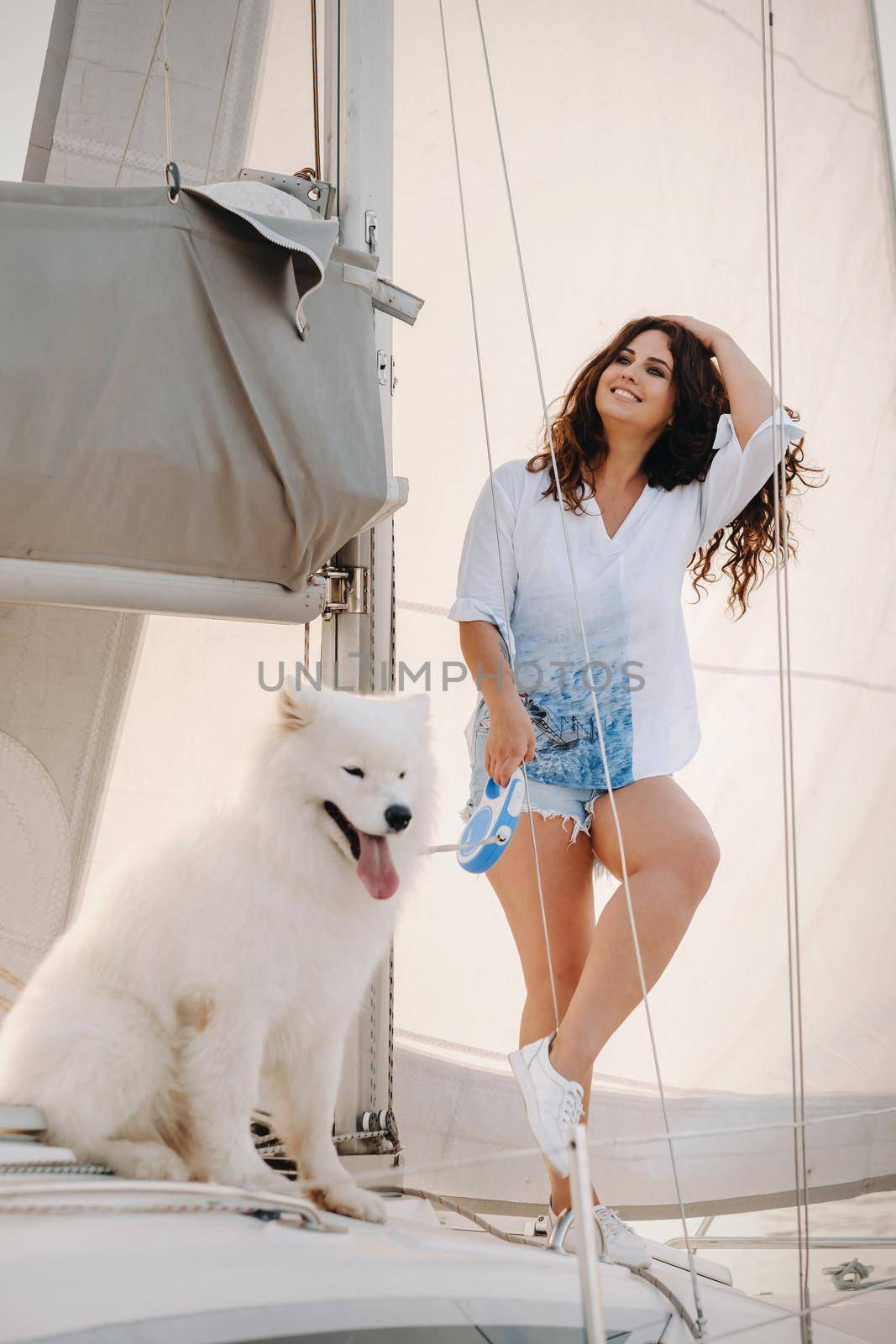 a happy woman with a big white dog on a white yacht in the sea.