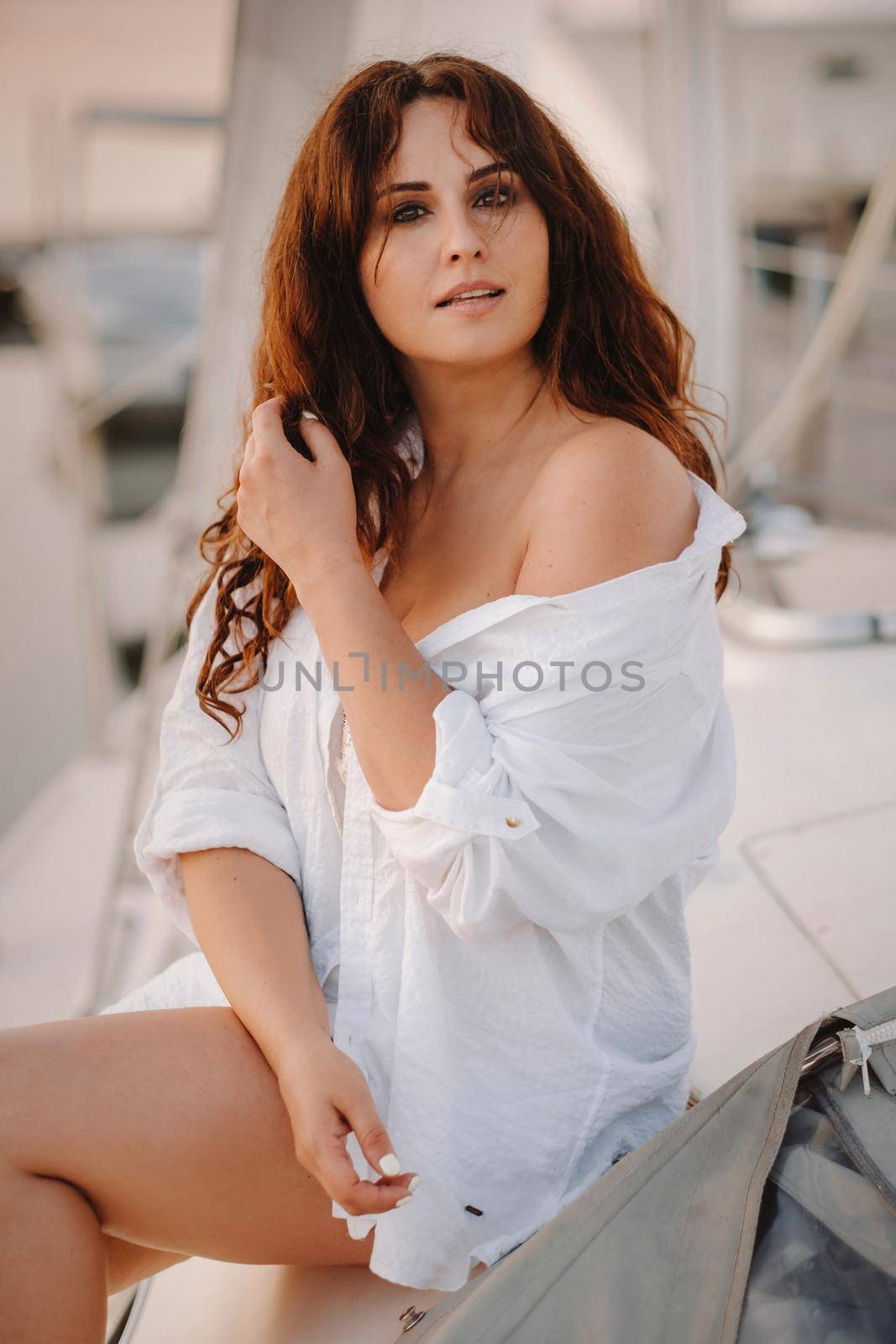sexy woman in a white shirt enjoys the sunset on her private white yacht.