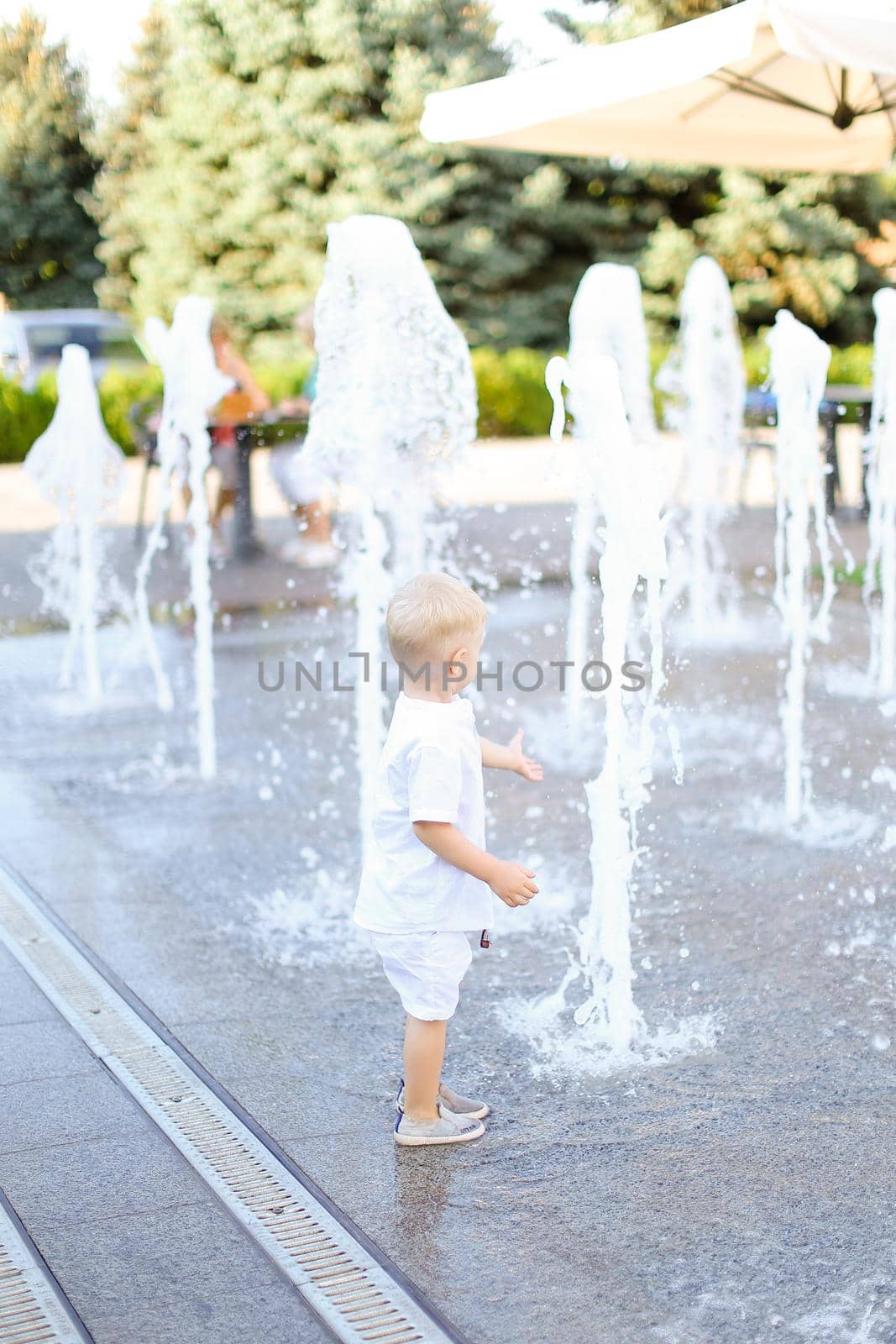 Little cute male baby walking near fountain. by sisterspro