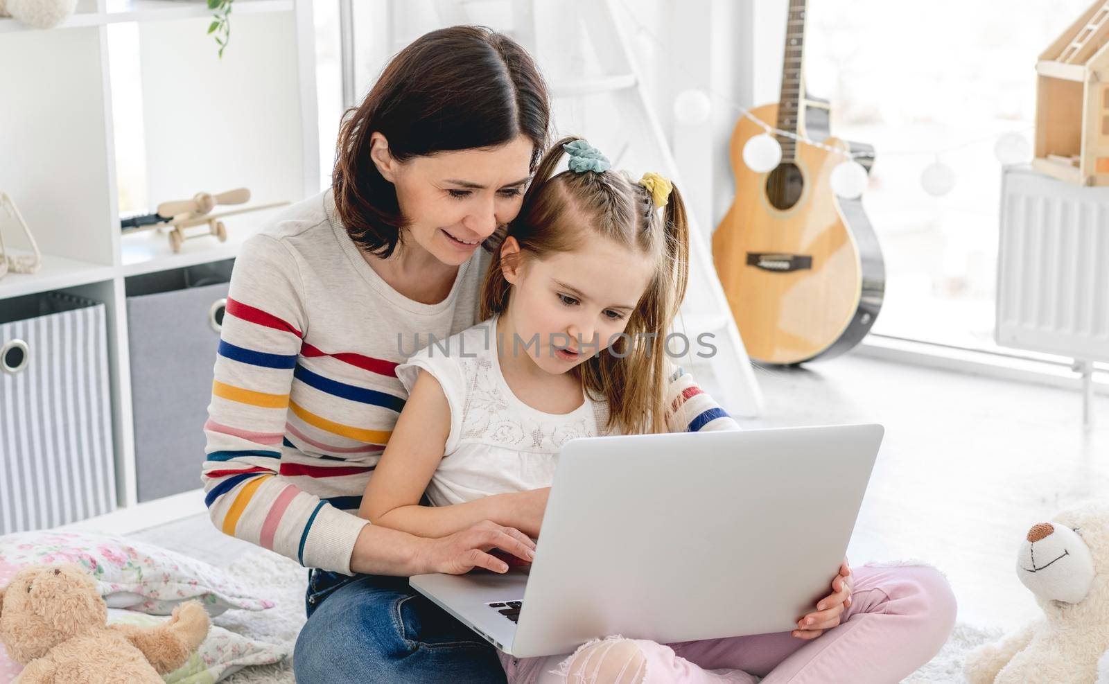 Beautiful mother with daughter playing on computer indoors