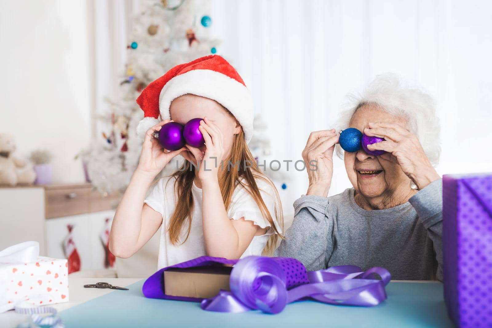 Smiling granddaughter in santa hat playing decorative balls at Christmas