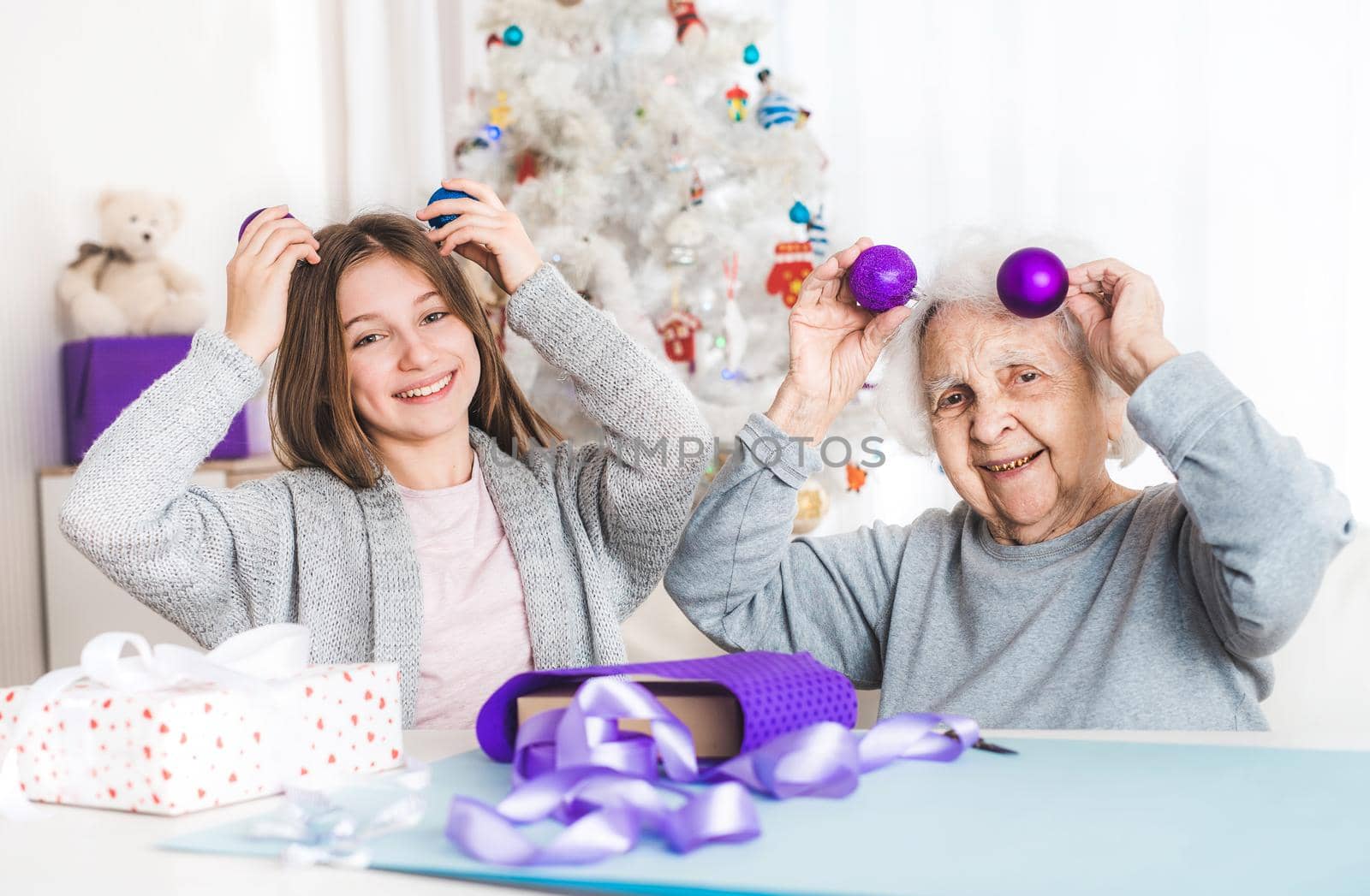 Smiling granddaughter ang grandma playing with decorative balls at Christmas