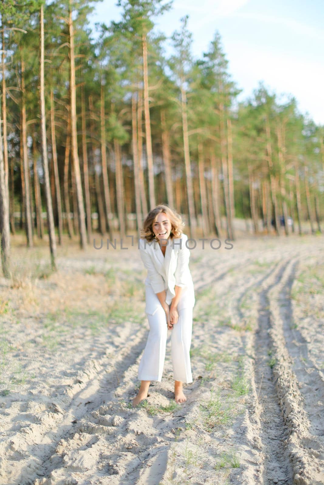 Blonde pretty woman walking on sand beach and wearing white clothes. by sisterspro